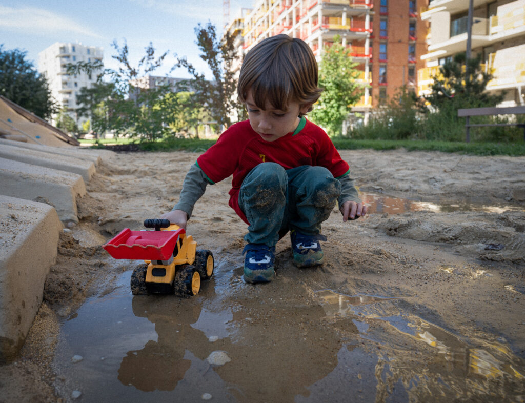 Child playing in the sand with a toy truck